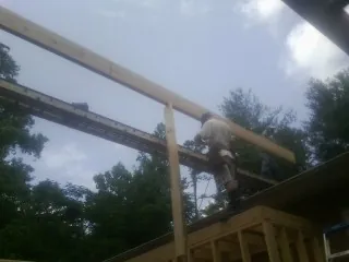 Carpenter setting a ridge beam over a new addition frame — Ice Dam Removal by Roofing Brothers in Poplar Grove