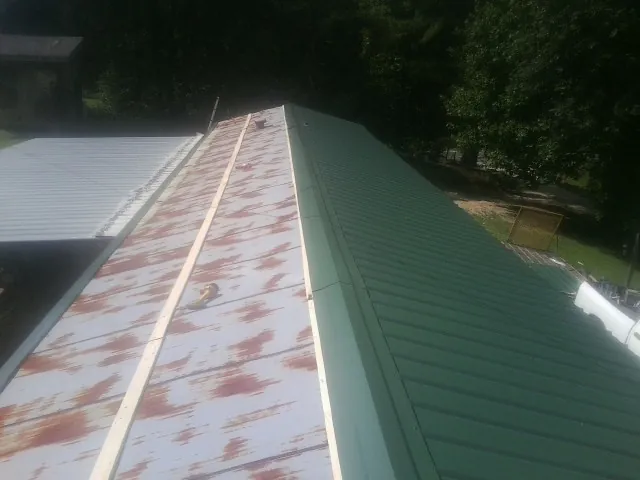 Old rusted panels beside newly installed green metal roofing — Wind Damage Roof Repair by Roofing Brothers in Poplar Grove