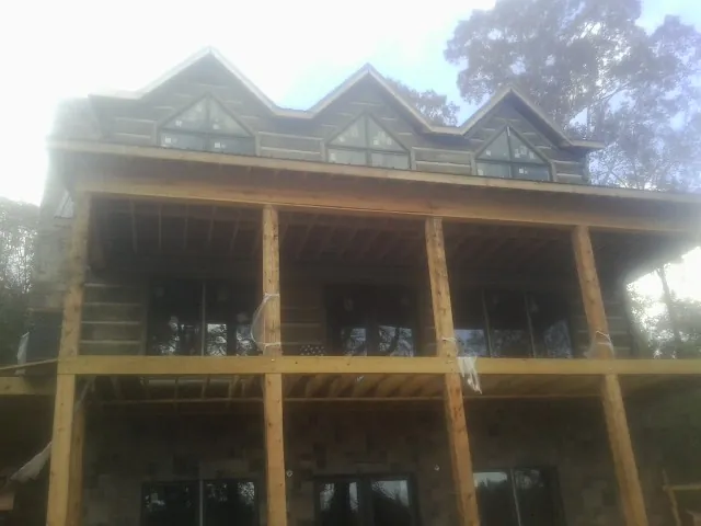 Dormers and porch framing on a large log home under construction — Roof Coating work by our crew in Poplar Grove
