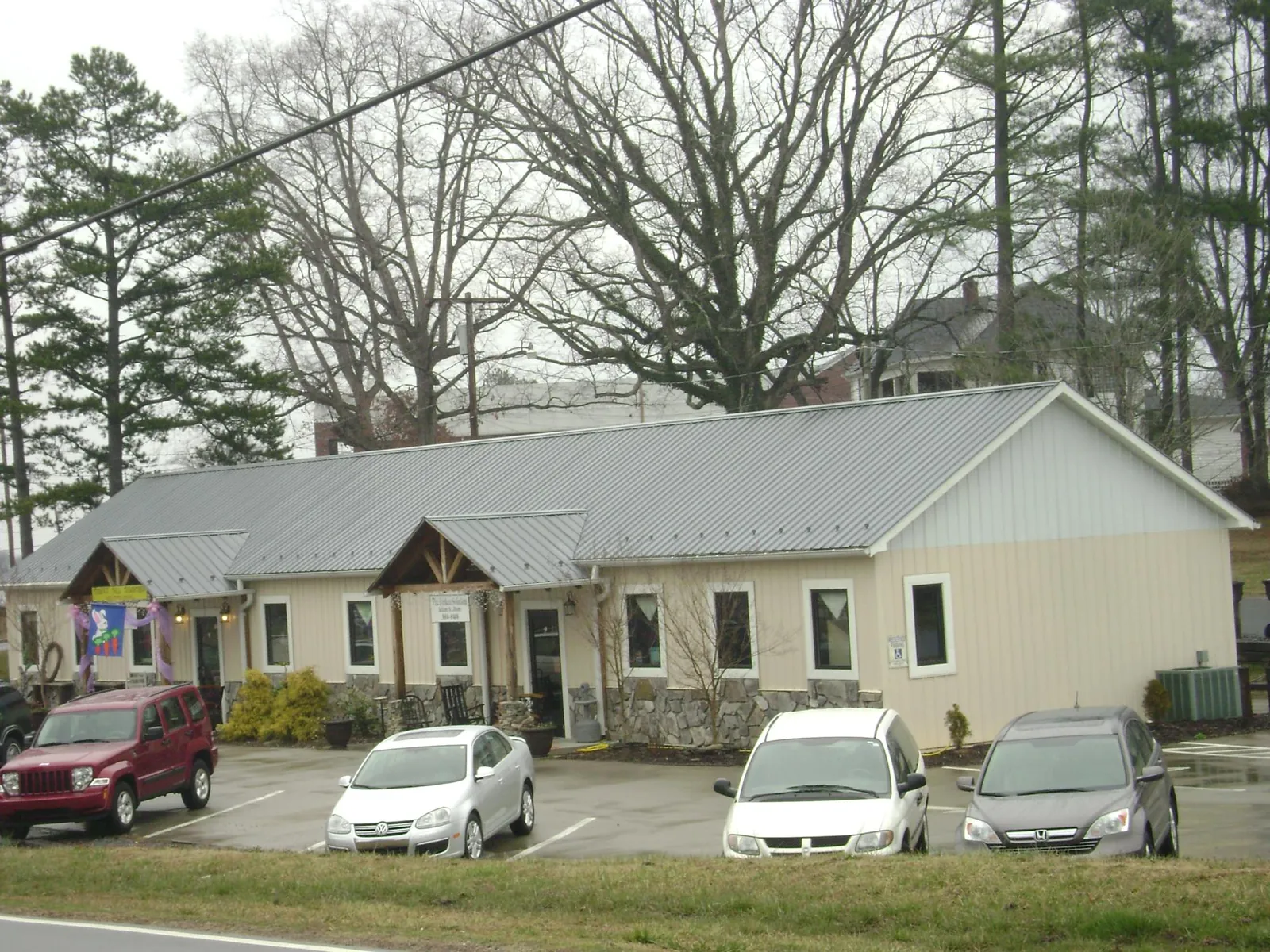 Gray metal roof with timber entry brackets on a small commercial building in Poplar Grove