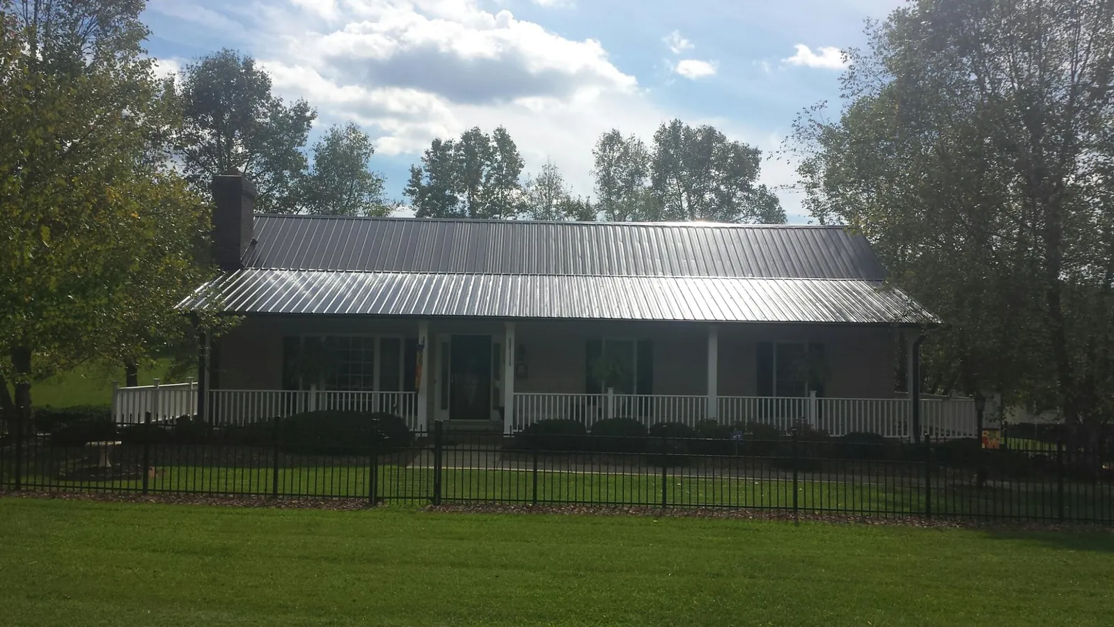 Gray metal roof on a brick ranch with a full width front porch — Gutter Guard Installation work by our crew in Poplar Grove