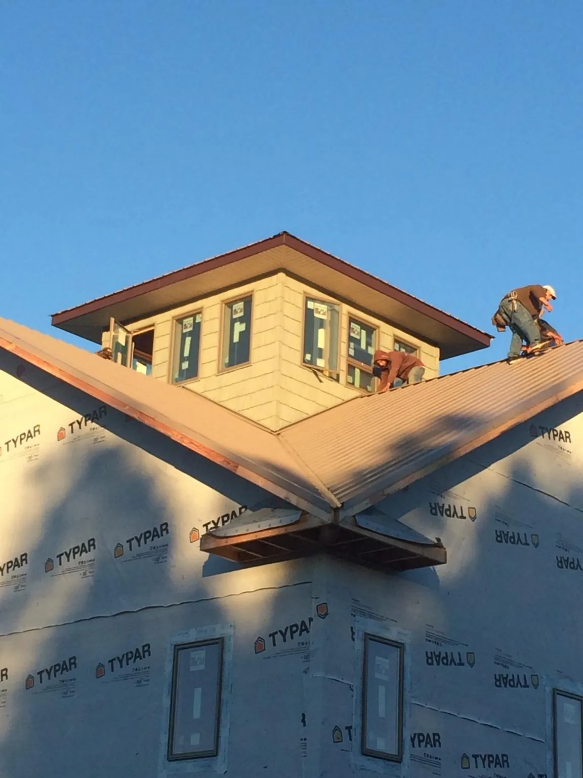 Roofers working around a rooftop cupola on a new metal roof at sunset — Roof Waterproofing in Poplar Grove by Roofing Brothers